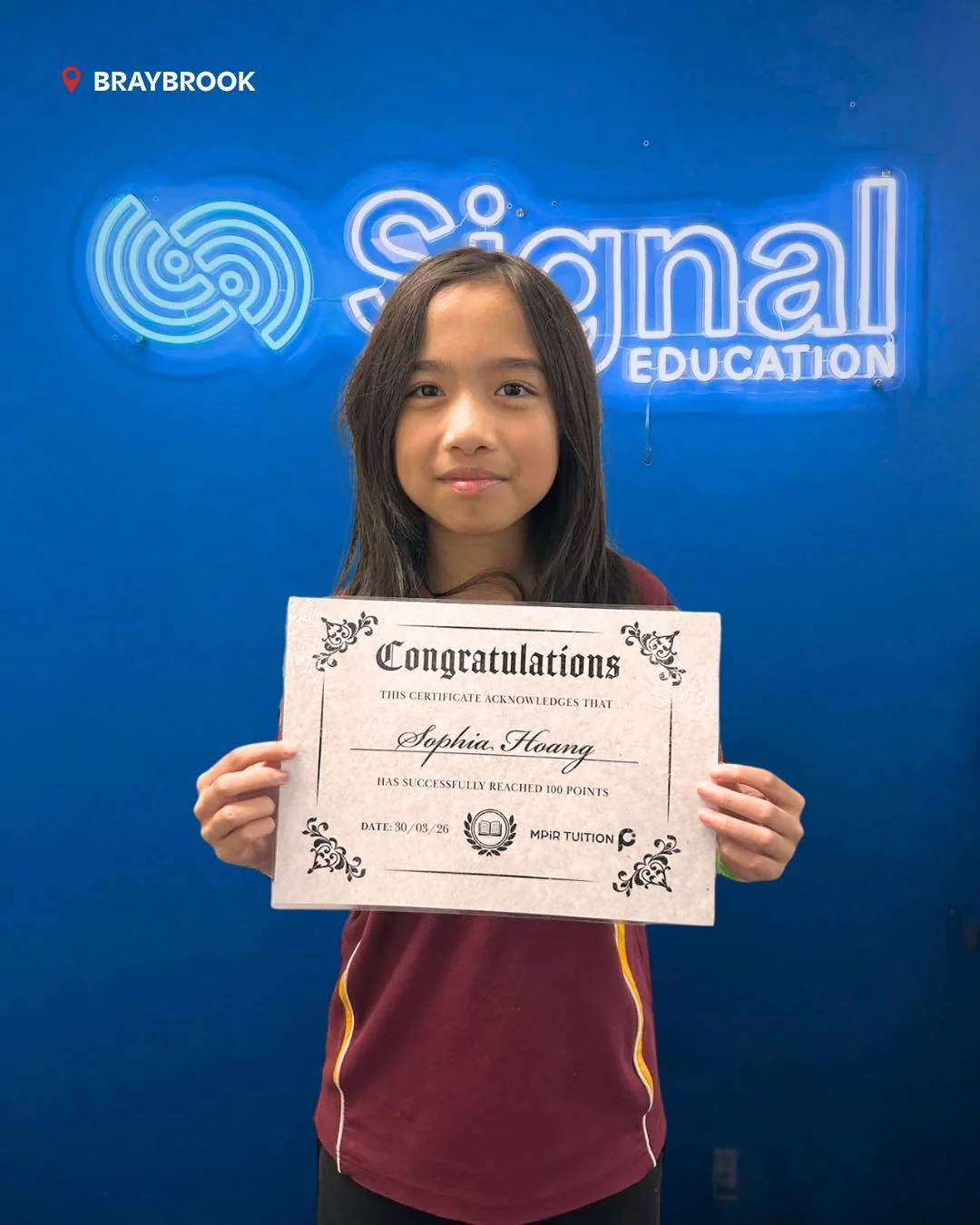 A Signal Education student holding a 100-point achievement certificate